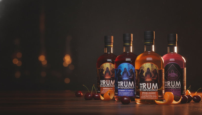 The Rum Infusionist signature rum range on a bar top in warm distillery light