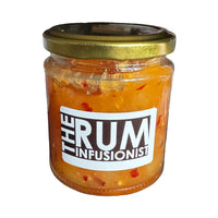 Jar of 'The Rum Infusionist' product on a reflective surface with plants in the background