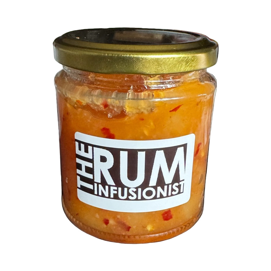 Jar of 'The Rum Infusionist' product on a reflective surface with plants in the background